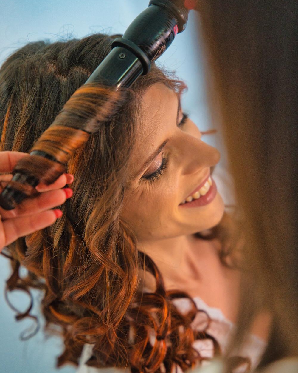 Aurore réalisant des boucles au fer pour une cliente