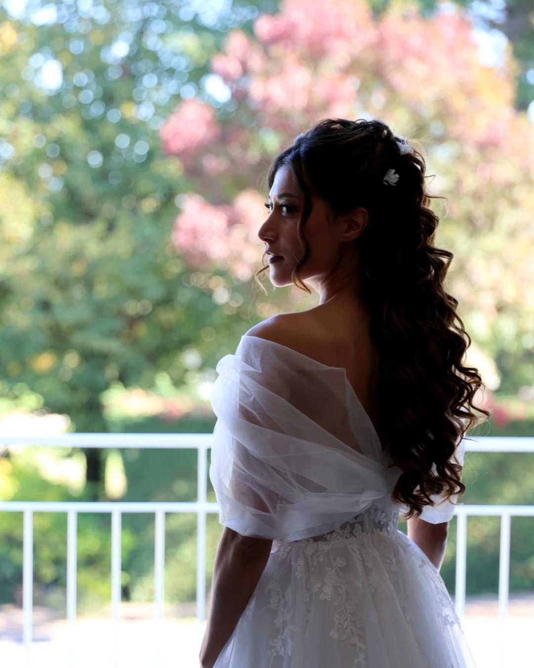 Mariée de profil avec une coiffure bouclée et un voile drapé
