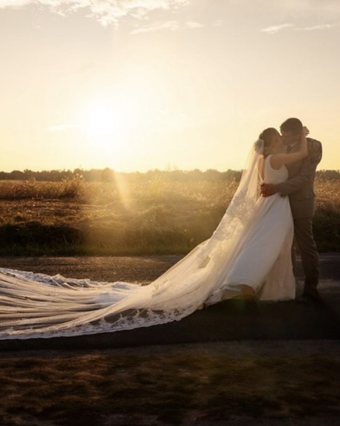Mariée et marié s'embrassant au coucher de soleil